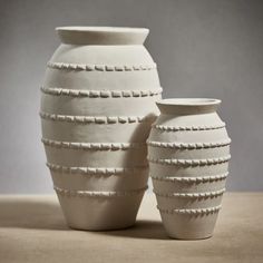 two white vases sitting next to each other on a table