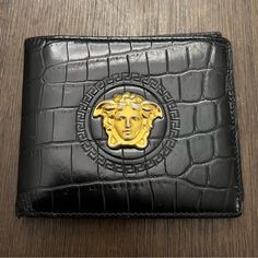 Authentic Versace Medusa Bifold Wallet With Crocodile Effect. Medusa 3d Emblem. Rarely Seen Croc Effect With 3d On This Wallet Still Available. Approx: 8.5 In Long By 3.5 In When Open. Depth Is About 0.5 In When Closed. There Is Wearing In Gold Tone Of Medusa, Rubbing On Corners And Fold Of Wallet At Edges, And Mild Scuffing/Scratches In Leather. Pen Tip Size Wear Through On Inside On Cc Slot. The Dimples Are Part Of Crocodile Pattern. 6 Card Slots With Small Area For Use Underneath. 2 Notes Locations. Really Clean Inside! See Pictures For All Details Sold As Is. Versace Bags, Crocodile Pattern, Leather Bifold Wallet, Bifold Wallet, Card Slots, Slots, Versace, Pen, Wallet