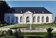 a large white house sitting on top of a lush green field next to a fountain