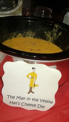 a bowl of soup on a table with a sign that says, the man in the yellow hat's cheese dip