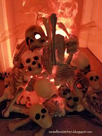 a pile of skulls sitting on top of a floor next to a fire place filled with candles