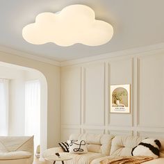 a living room filled with furniture and a white cloud shaped light fixture above the couch