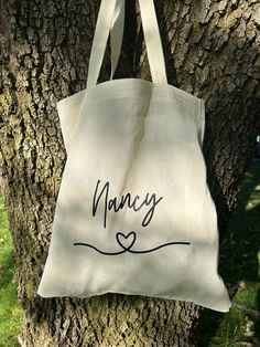 a canvas bag hanging on a tree with the word fancy written in cursive writing