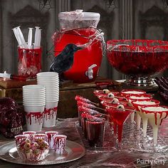 a table topped with lots of red and white desserts next to cups filled with liquid