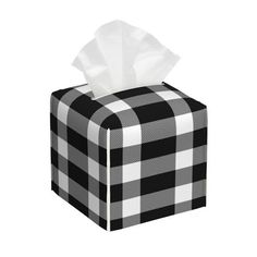 a black and white checkered tissue box with tissue paper on the lid, in front of a white background