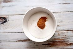 a white bowl filled with brown powder on top of a wooden table