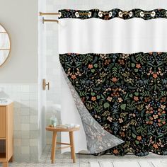 a bathroom with a shower curtain that has flowers on it and a mirror behind it