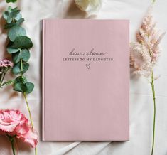 a pink book with the words dear sloan letters to my daughter on it next to flowers