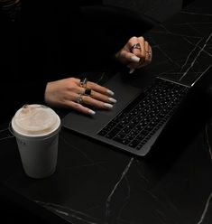 a woman sitting at a table with a laptop and cup of coffee in front of her