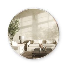 a living room filled with furniture and a round mirror above it's coffee table