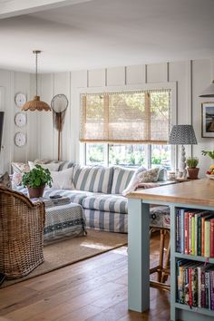 a living room filled with furniture and a book shelf next to a kitchen island in front of a window