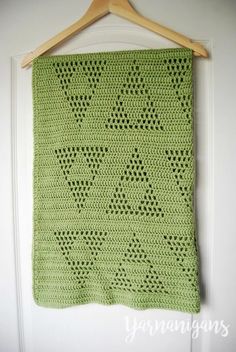 a green crocheted blanket hanging on a wall