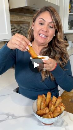 a woman sitting at a kitchen counter eating french fries