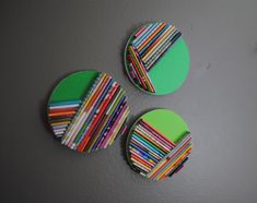 three circular magnets with colored strips on them sitting on a wall next to each other