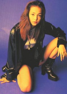 a woman sitting on the ground with her legs crossed and wearing black boots, posing for a photo