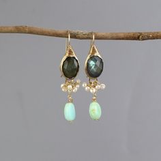 These rich and glamorous Ronit earrings are bezel set with a gorgeous labradorite gemstone and a dainty cluster of pearls. A single Peruvian opal dangles down gently. Wire wrapped gold filled details give these earrings a very unique and artistic look. A total statement piece with lots of elegance, you'll have lots of fun wearing these!   Measurements: Length (including hook): approx. 5cm  Labradorite: 10x14mm Materials: Stone: labradorite, pearls, Peruvian opal Metal: sterling silver bezel and gold filled Hook: gold filled Natural labradorite gemstone has lines and cleavage lines, and its fascinating color varies from grey and blue shades to green shades.  Labradorite Gemstone meaning:  Transformation ~ Promotes psychic abilities ~ Strengthens our will ~ Stimulates imagination ~ Calming Pearl Cluster Earrings, Peruvian Opal, Gemstone Meanings, Labradorite Earrings, Pearl Cluster, Lovely Ring, Cluster Earrings, Opal Earrings, Gold Filled Jewelry