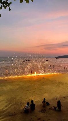 people are sitting on the beach at sunset