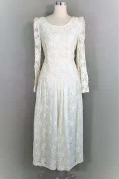 "This is a pretty lace dress with beaded bodice, drop waist , and full skirt. It is in good vintage condition and is without holes, stains, or tears. Marked size 12 38\" bust 30\" waist 40\" hip 51\" nape to hem Purveyor's Note: We have searched far and wide, wrestled bears, braved the cold, traversed mountain ranges, fought pirates, swam with sharks and eaten at many a questionable road side taco stand to provide our customers with one of a kind vintage pieces. Know that whichever piece you cho Vintage Dress With Delicate Lace And Fitted Bodice, Vintage White Lace Dress With Fitted Bodice, Vintage Dresses With Delicate Lace For Vintage Events, Vintage Fitted Lace For Wedding, Vintage Lace For Evening, Fitted Vintage Dress With Delicate Lace, Vintage Lace Bodice Dress For Vintage Events, Vintage Lace With Lace Bodice For Weddings, Vintage Dresses With Lace Bodice For Vintage Events