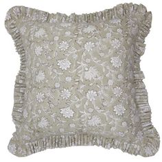 a decorative pillow with ruffled edges and flowers on the front, in light grey