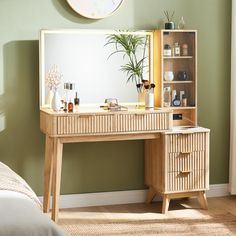 a wooden desk topped with a mirror next to a bed