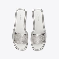 The classic sport slide, streamlined and refined. A trim band, padded in crinkled metallic leather. A slim cushioned sole for comfort and flexibility. Finished with a Double T, topstitched and oversized for a subtle statement. Luxury Slides With Textured Footbed For Spring, Classic Slides With Textured Sole For Spring, Classic Spring Slides With Textured Sole, Silver Slides With Removable Insole, Silver Leather Slides With Cushioned Footbed, Silver Slides With Leather Footbed For Summer, Casual Silver Leather Slides, Silver Casual Slides With Cushioned Footbed, Casual Silver Slides With Cushioned Footbed