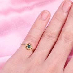 a woman's hand wearing a gold ring with an emerald stone in the middle