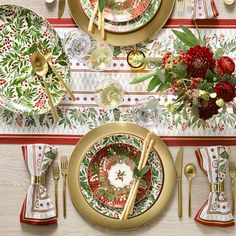 the table is set with red and green plates, silverware, and gold cutlery