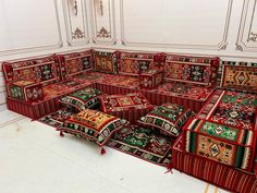 a room filled with lots of red and green rugs on top of each other