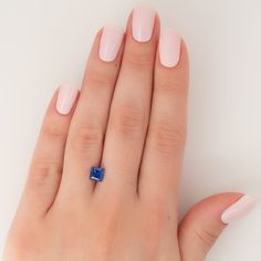 a woman's hand with pink nails and a blue diamond ring on her finger