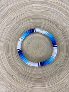 a blue and white beaded bracelet is in the center of a circular wooden bowl