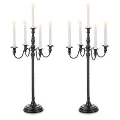 two black candelabras with white candles on them