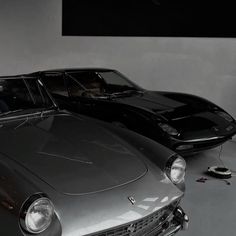 two classic sports cars are parked in a garage