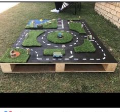 a table made out of wood with grass and toys on it in the shape of a road