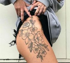 a woman's thigh with flowers on it and her hand resting on the thighs