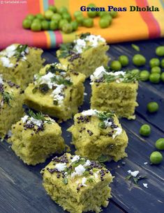 green pea dhoka is cut into squares on a wooden table with peas scattered around it