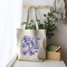 a tote bag with purple flowers on it sitting next to a window sill