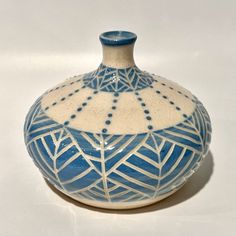 a blue and white vase sitting on top of a table next to a white wall