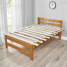 a wooden bed frame with slats on the bottom and foot board, in front of a window