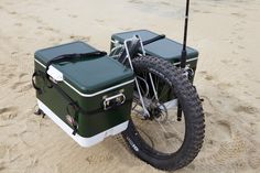 a bike with two coolers attached to it on the beach