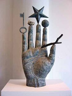 a sculpture of a hand with scissors and stars on it's fingers is shown in front of a white wall