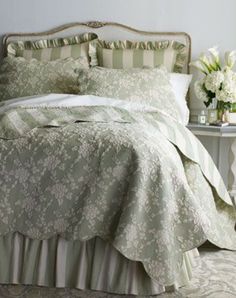 a bed with green and white bedspread in a room next to a table