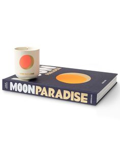 a coffee cup sitting on top of a book with the title moon paradise next to it