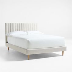 the bed is made up with white linens and wood legs on each side, while the headboard has been turned off