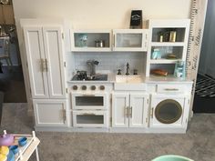 a toy kitchen with white cabinets and appliances in it's display area, including a washing machine