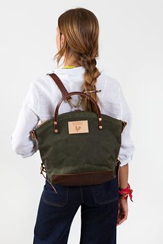 Model wearing olive colored back pack style bag with brown leather straps Waxed Canvas Tote Bag, Wax Canvas, Lynchburg Virginia, Waxed Canvas Backpack, Waxed Canvas Bag, Crossbody Backpack, English Bridle, Convertible Backpack, Key Clip