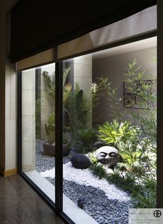 an indoor garden with rocks and plants in the center is seen through large glass doors