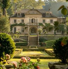 a large house with lots of trees and bushes around it's front entrance, as seen from across the garden