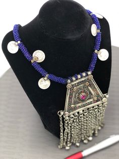 * This handmade Afghani Kuchi style Necklace is a magnificent piece of art as it carries all the elements which make this ethnic ornament authentic traditional wear. * This necklace has intricately carved designs and multicolor stones carved into the pendent making the ornament more ravishing and tempting. * The lower part of the artifact has been embellished with silver dangling beads connected to the pendant with long chains. Not only that the blue beads rolled around the thread has complement Handmade Bohemian Medallion Necklace, Traditional Handmade Pendant Beads, Traditional Handmade Silver Medallion Necklace, Traditional Silver Medallion Necklace, Bohemian Beaded Medallion Necklace, Bohemian Medallion Pendant Necklace For Festival, Traditional Festival Beaded Necklaces, Traditional Beaded Necklace For Festivals, Bohemian Pendant Medallion Necklace For Festivals