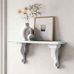 a white shelf with two vases and flowers on it next to a framed photograph