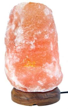 an orange himalayan salt lamp on a wooden base